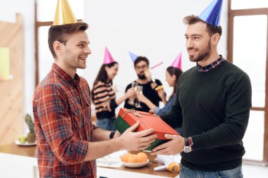 Erkekler hediye kutusunu tutuyor ve birbirlerine gülümsüyorlar.