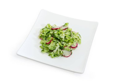 Sebze salatası yapılmış taze genç lahana, salatalık, kırmızı turp dilimlenmiş ve kare beyaz tabak üzerinde beyaz bir arka plan üzerinde yeşil soğan kıyılmış