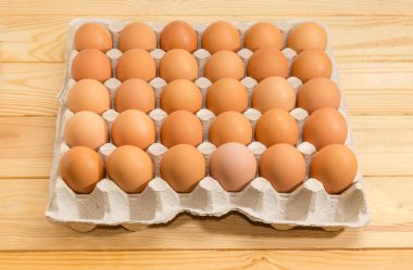 Geri dönüşümlü kağıt üzerinde bir açık renkli ahşap yüzey kahverengi tavuk yumurtası büyük karton yumurta tepsi ambalajında otuz yumurta için yapılmış