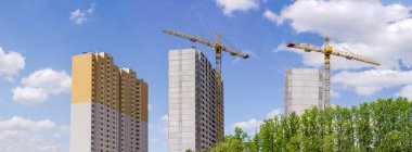 Kule vinç ve ağaçlar gökyüzü karşı ön planda bina ile prekast beton panelleri çok hikaye konut inşaatı Panoraması evler