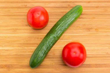 Taze salatalık ve bambu kesme tahtası closeup iki domates ile yüzde işareti konmuş