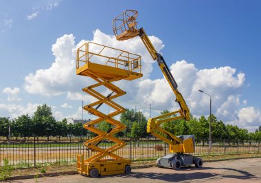 Sarı kendinden tahrikli Asansör boom Asansör ve makas ağaçlar ve gökyüzü arka plan üzerinde Belden kırma modeller
