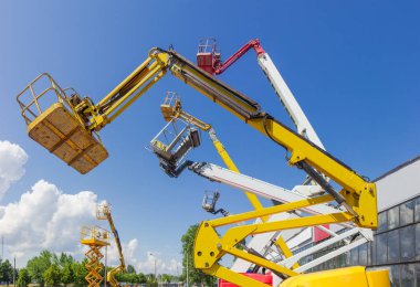 Bomlar sepetleri ve en iyi parçalar farklı mafsallı boom liftleri ve makas ile parçası endüstriyel yapı ve gökyüzü arka plan üzerinde kaldırdı