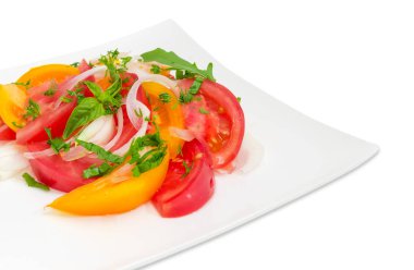 Beyaz kare yemek parçası taze sebze salatası ile beyaz bir arka plan üzerinde kırmızı ve sarı domates, soğan ve Yeşiller yakın çekim dilimlenmiş