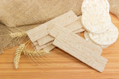 Kuru dikdörtgen düz Çavdar-buğday net-ekmek ve kahvaltılık pirinç gevrek ekmek yuvarlak ve bir ahşap yüzey kulaklara buğday