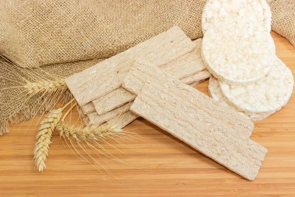 Kuru dikdörtgen düz Çavdar-buğday net-ekmek ve kahvaltılık pirinç gevrek ekmek yuvarlak ve bir ahşap yüzey kulaklara buğday