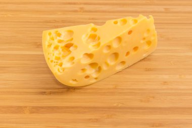 Bambu kesme tahtası üzerinde iç delikleri ile orta-sert Swiss peynir parçası