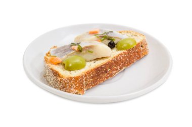 Kahverengi buğday filizlenmiş ekmek, beyaz bir arka plan üzerinde seçici odak, bir uçan daire portre üzerinde yeşil zeytin ve turşu Atlantik ringa balığı filetosu dilim açık sandviç yaptım