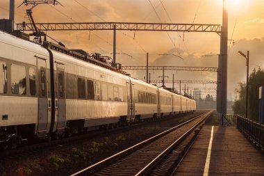 Hızlı şehirlerarası tren günbatımı arka plan üzerinde hareketli şehir demiryolu bölümünü