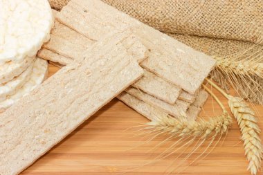 Dikdörtgen düz Çavdar-buğday crispbreads kuru ve ahşap bir yüzey üzerinde şişirilmiş pirinç crispbreads ve buğday kulakları yuvarlak
