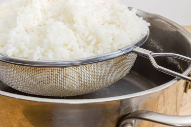 Paslanmaz çelik elek ile parça haşlanmış ve paslanmaz çelik stok pot yakın çekim üzerinde beyaz pirinç seçici odak yıkanmış