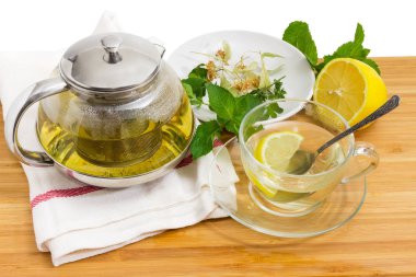 Bitkisel çay süzgeç ile cam Çaydanlık ve cam fincan, limon ve çay hazırlama daire ahşap bir yüzeyi tarih için otlar