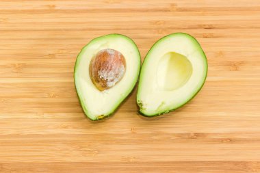 Avokado meyve armut biçimli yeşil derili bambu kesme tahtası üzerinde ikiye böldüm