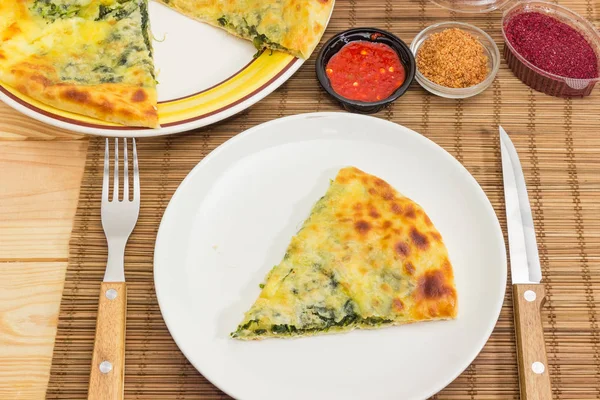 Yemek parçası kısmen khachapuri, diğer çanak, çatal, bıçak ve baharat bambu yer mat yakın çekim üzerinde üzerinde bir dilim dilimlenmiş