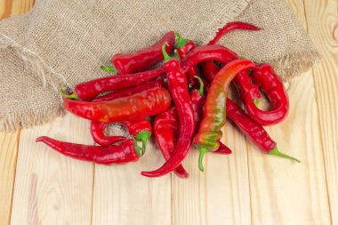 Taze kırmızı biber biber bir çuval bezi ve hafif renkli ahşap rustik masa