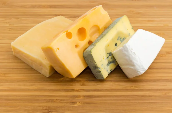 在竹切板特写的蓝色奶酪 中硬的瑞士和硬奶酪件 — 图库照片