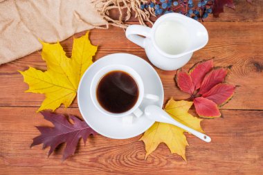 Beyaz taze yapılmış kahve fincan süt sonbahar yaprakları ve kadın eşarp ile eski rustik ahşap masa seramik kaşık şeker ve süt sürahi ile üstten görünüm üzerinde uçan daire