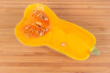 Olgun sarı-turuncu butternut squash ahşap bambu kesme tahtası üzerinde yarısı