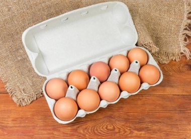 Üstten görünüm açık yumurta kartonu geri dönüşümlü kağıt hamuru çul bir ahşap rustik masada yapılmış on yumurta için kahverengi tavuk yumurta