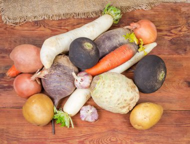 Çeşitli yıkanmış değil soyulmuş pişmemiş kök sebzeler onların deri yığını üstten görünüm eski koyu renkli ahşap rustik masa