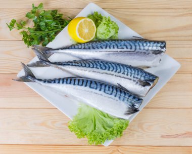 Pişmemiş yıkılmış başsız leşleri, uskumru, limon ve taze yeşillik meydanında bir ahşap rustik masada yemek