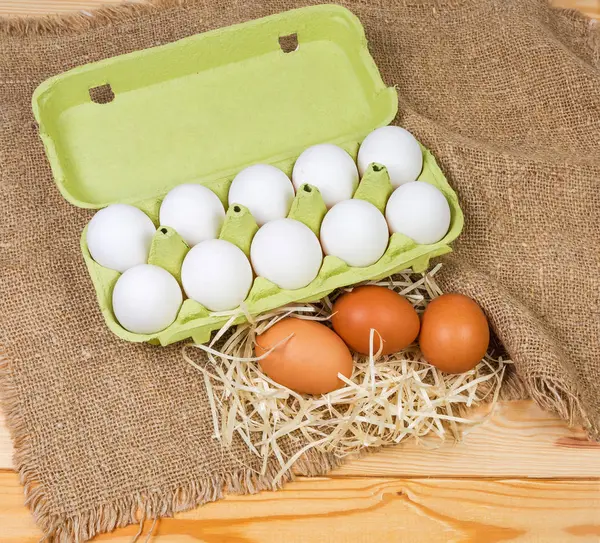 用回收纸浆和棕色鸡蛋在乡村餐桌上用麻布分别制成的开式鸡蛋盒中的白色鸡蛋 — 图库照片