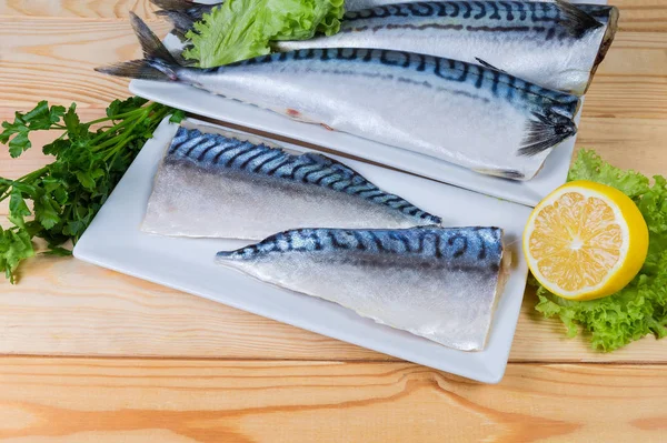 在乡村餐桌上的盘子里 用植物油将大西洋鱼的盐片与生无头鱼的尸体 柠檬和青菜相对应 — 图库照片
