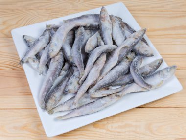 Buzlu sır ve hoarfrost Ahşap Masa kare beyaz bir tabak üzerinde donmuş Baltık Ringa kaplı