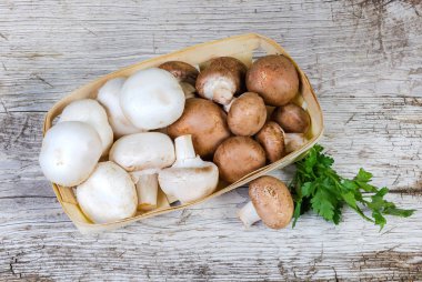 Üstten Görünüm düğmesinin ekili ham beyaz ve kahverengi ahşap sepet ve maydanoz bir eski kırık ahşap yüzeyde mantar