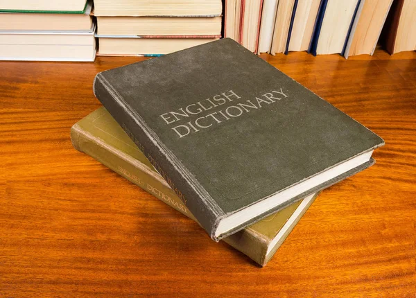 大きな古いハードカバー英語の辞書の他の本の背景に木製のテーブルのカバー付きの つのボリューム — ストック写真