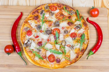 Tavuk eti, sosis, düğme mantar, domates ve roka, ayrı ayrı kiraz domates ve biber ile pişmiş pizza üstten görünüm ahşap kesme tahtası üzerinde