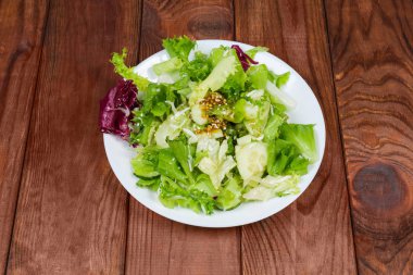 Salata yaprağı yeşil ve kırmızı marul çeşitleri çanak üzerinde hardal salata sosu ile eski koyu renkli ahşap rustik masa