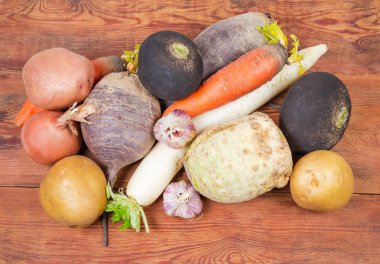 Çeşitli yıkanmış değil soyulmuş pişmemiş kök sebzeler onların deri yığını üstten görünüm eski koyu renkli ahşap rustik masa