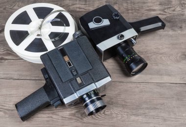 Powered by clockwork motor ve elektrik motoru ve makaraları sinema filmleri süper 8 mm Format eski bir ahşap yüzeyde iki eski vintage Amatör film film kameralar
