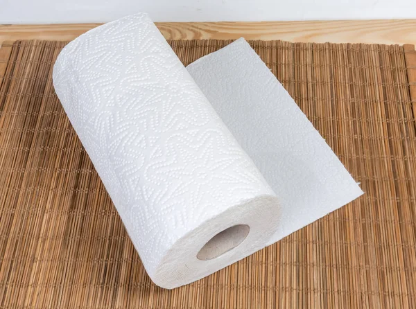 Roll of two-ply paper towels with tear-off sheets on the wooden bamboo table mat