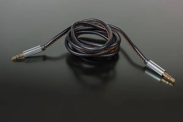 High-fidelity analog shielded audio cable with gold-plated stereo connectors mini jack on a dark matt surface