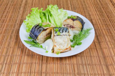 Uskumru, marul, soğan ve yeşillik bir bambu masa mat beyaz tabak üzerinde pişmiş dilim