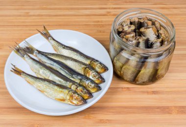 Uçan daire Baltık ringa ve bitkisel yağ cam bir bambu ahşap yüzeyde korunmuş başsız Baltık ringa balığı füme