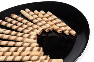 Beyaz bir arka plan üzerinde krem çikolata dolum çizgili gofret ile siyah çanak parçası tüpler