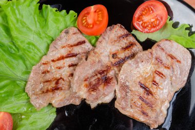 Özlü domuz biftek ile siyah çanak closeup sebze ızgara