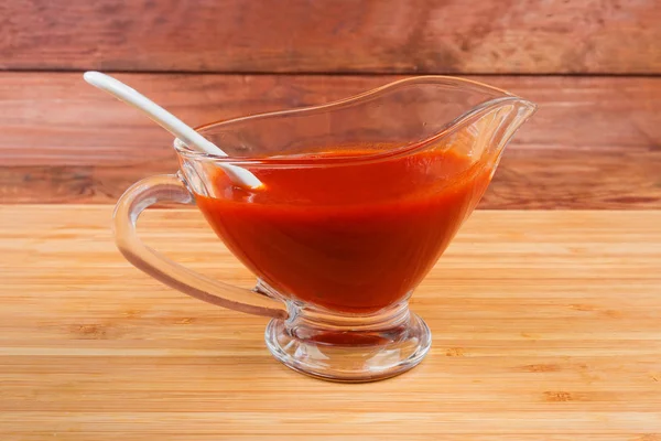 Томатный соус в стеклянном соусе с белой керамической ложкой — стоковое фото
