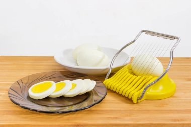 Bütün ve dilimlenmiş yumurta ve yumurta dilimleyici ahşap yüzey üzerinde
