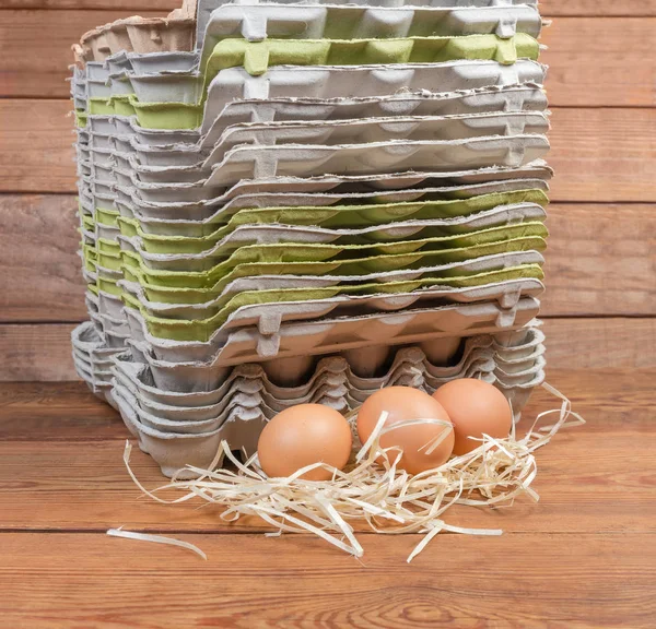 Chicken eggs against of stack of empty pulp egg cartons