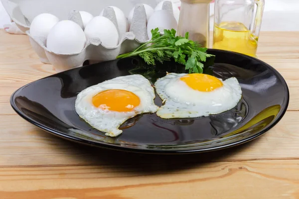 Fried eggs prepared sunny side up on dish and ingredients