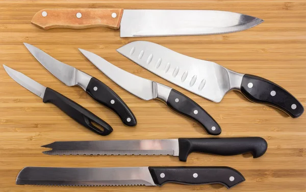 Background of different kitchen knives on the bamboo cutting board