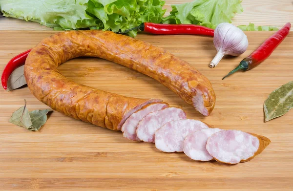 Частично нарезанная колбаса из колбасы среди специй и овощей — стоковое фото