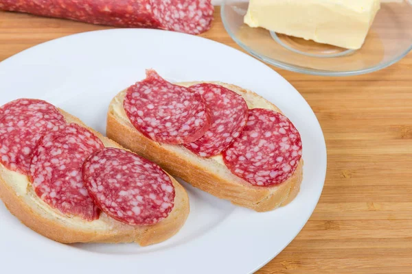 Sanduíches abertos com salame em tábua de corte de bambu — Fotografia de Stock