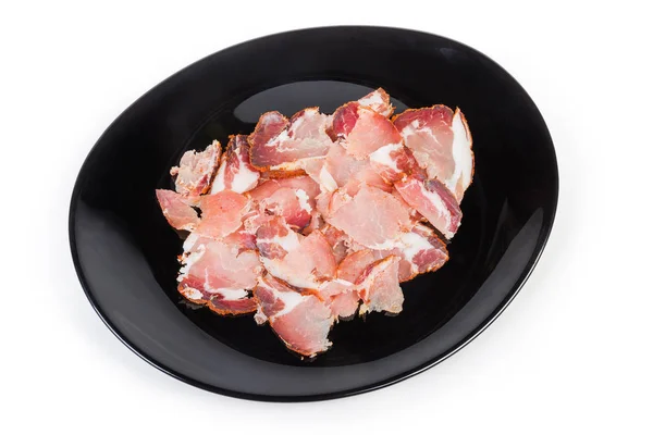 Dünne Scheiben vom getrockneten Schweinehals auf schwarzem Teller — Stockfoto
