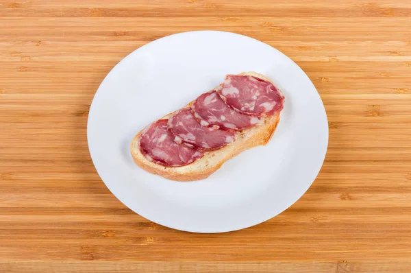 Offenes Sandwich mit trockener Wurst auf weißem Teller — Stockfoto