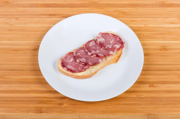 Sanduíche aberto com salsicha curada a seco em prato branco — Fotografia de Stock